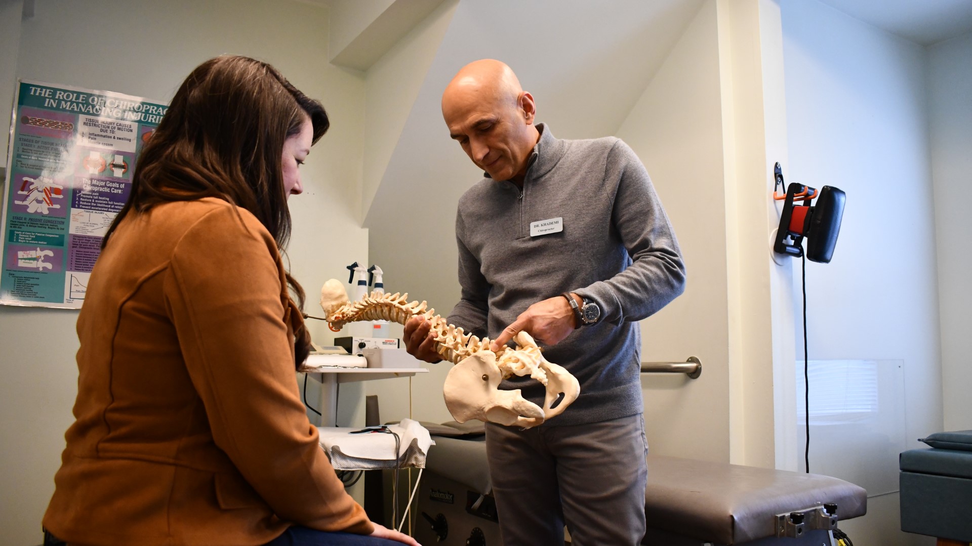 Dr. Khademi using a model spine as a visual aid.